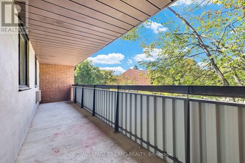 A balcony with a metal railing and a view of trees and a house.