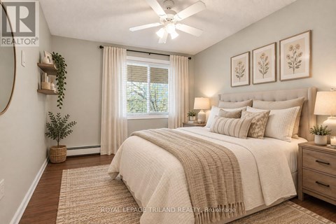 A bedroom with a large bed, a ceiling fan, and a window with curtains.
