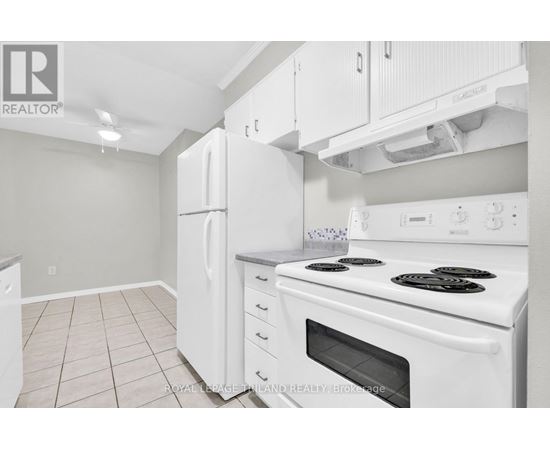 A white kitchen with a stove top oven and a refrigerator.