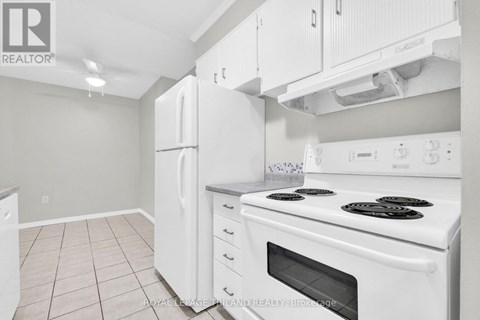 A white kitchen with a stove top oven and a refrigerator.