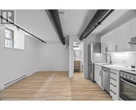 A kitchen with white cabinets and a wooden floor.