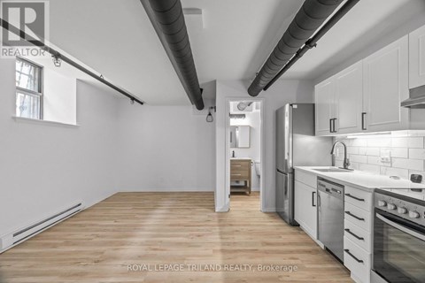 A kitchen with white cabinets and a wooden floor.