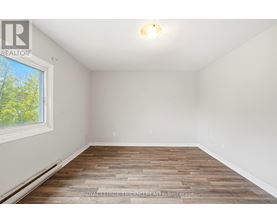 A room with wooden flooring and a window showing trees outside.