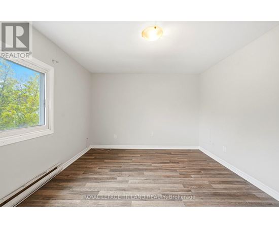 A room with wooden flooring and a window showing trees outside.