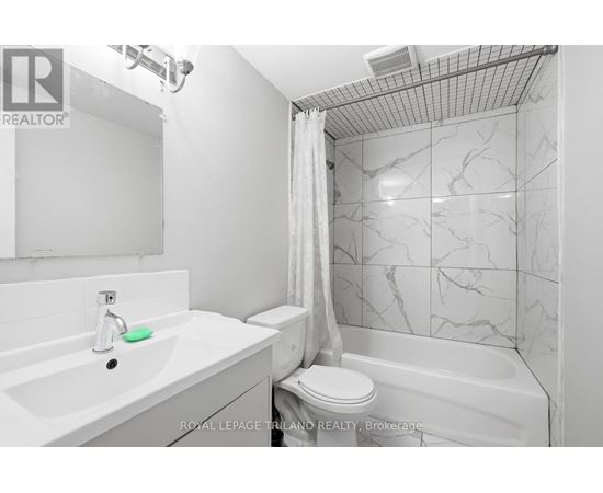 A white bathroom with a marble tile shower.