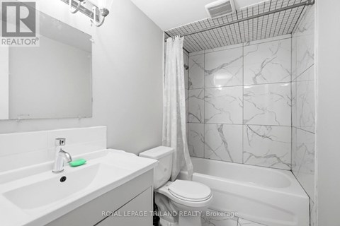 A white bathroom with a marble tile shower.