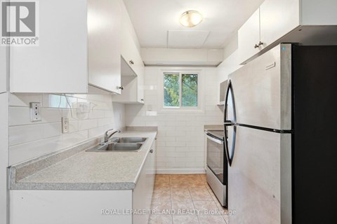 A kitchen with white cabinets and a black refrigerator.