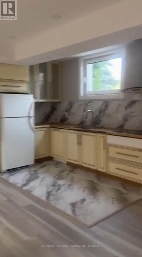 A kitchen with a white refrigerator and marble flooring.