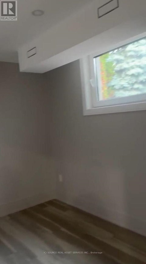 A room with a window and a wooden floor.