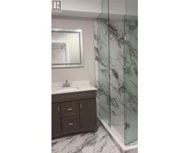 A bathroom with a marble floor and a glass shower stall.
