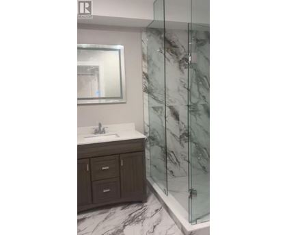 A bathroom with a marble floor and a glass shower stall.