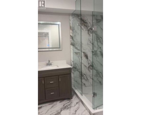 A bathroom with a marble floor and a glass shower stall.