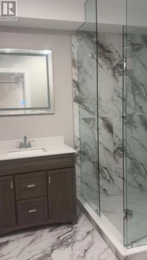 A bathroom with a marble floor and a glass shower stall.