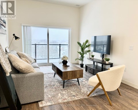 A living room with a grey couch, a wooden coffee table, a white chair, and a flat screen TV.