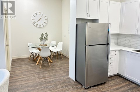 A kitchen with a refrigerator, table and chairs.