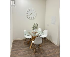 A glass dining table with four chairs and a clock on the wall.