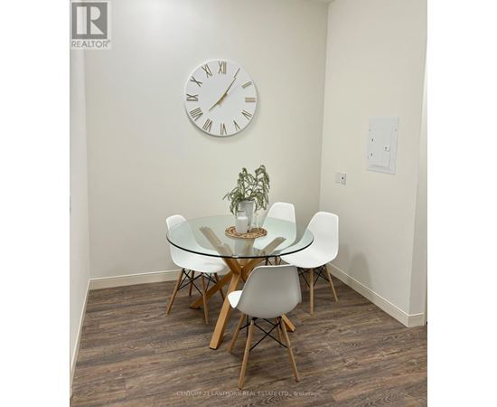 A glass dining table with four chairs and a clock on the wall.