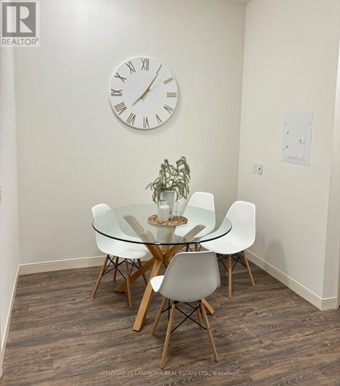 A glass dining table with four chairs and a clock on the wall.