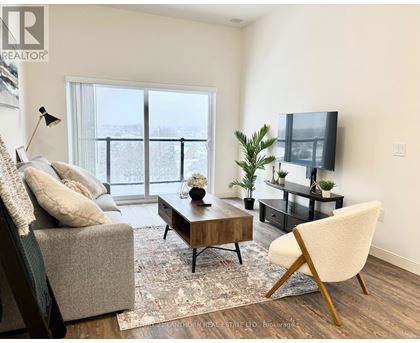 A living room with a grey couch, a wooden coffee table, a white chair, and a flat screen TV.