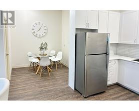A kitchen with a refrigerator, table and chairs.