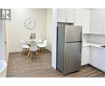 A kitchen with a refrigerator, table and chairs.