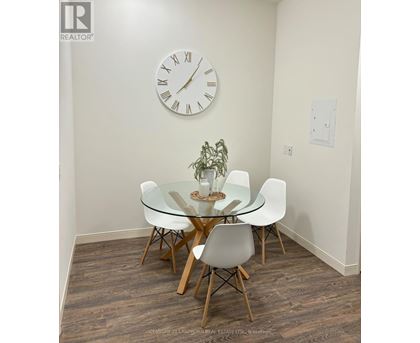 A glass dining table with four chairs and a clock on the wall.
