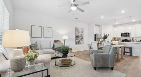 A well-lit living room with a glass coffee table and a grey armchair.