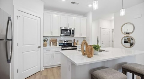 A kitchen with white cabinets and a white island with a plant on it.