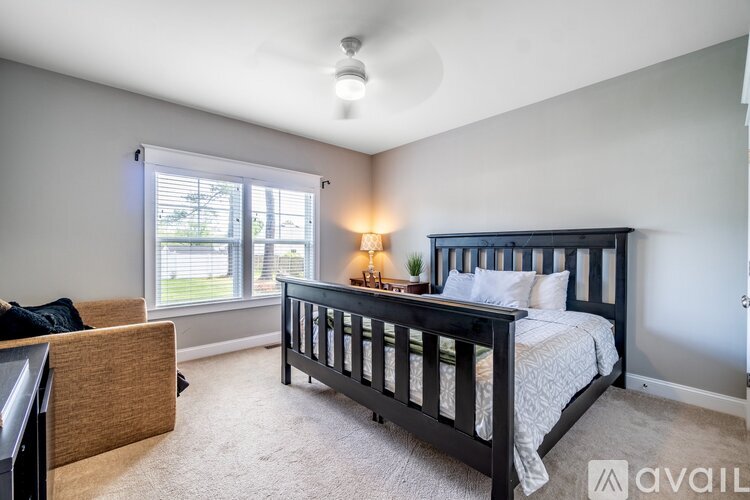 A bedroom with a large bed and a window with blinds.
