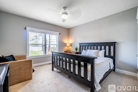 A bedroom with a large bed and a window with blinds.