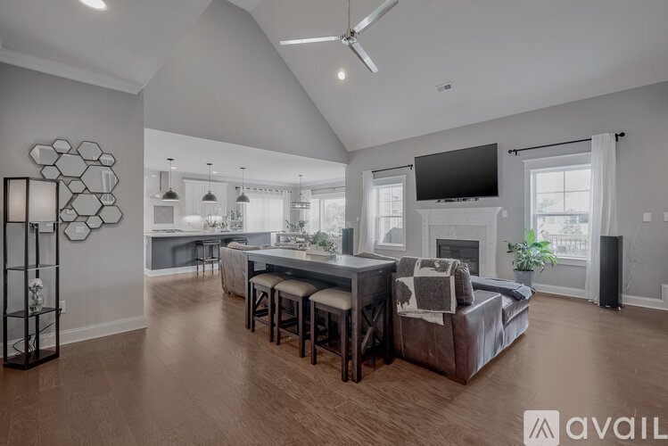 A spacious living room with a large couch and a television mounted on the wall.