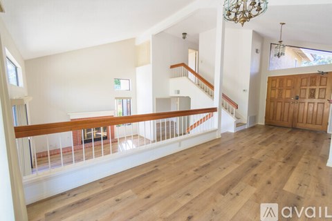A spacious living room with wooden floors and a staircase leading to the upper level.