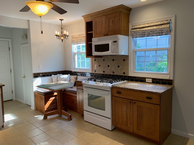 A kitchen with a white microwave above a stove and a table with chairs.
