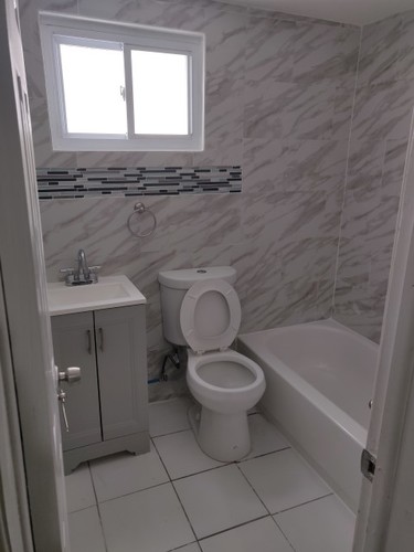 A white toilet sits in a bathroom with a marble wall.