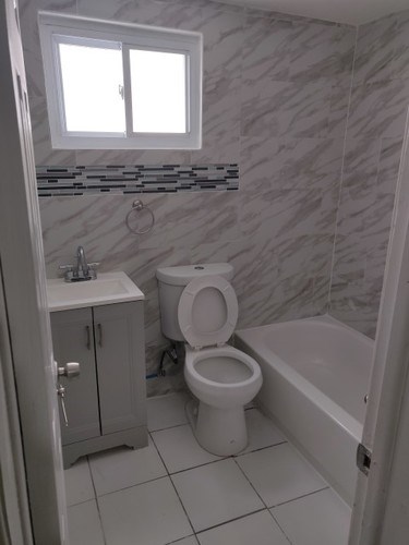 A white toilet sits in a bathroom with a marble wall.