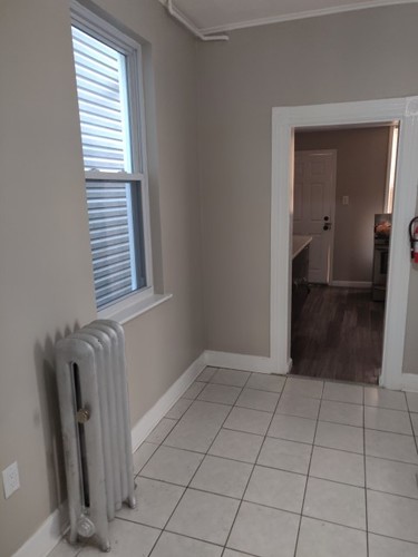 A room with a white tile floor and a window with blinds.