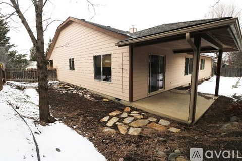 A small house with a porch and a covered entrance is surrounded by snow.