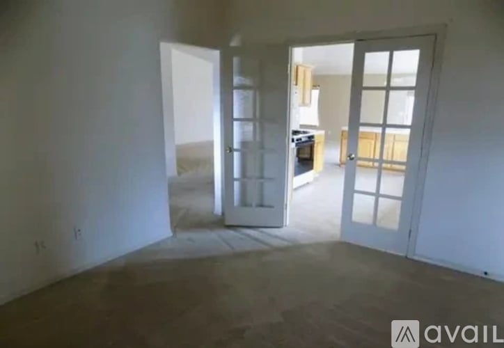 A room with a white wall and a door leading to another room.