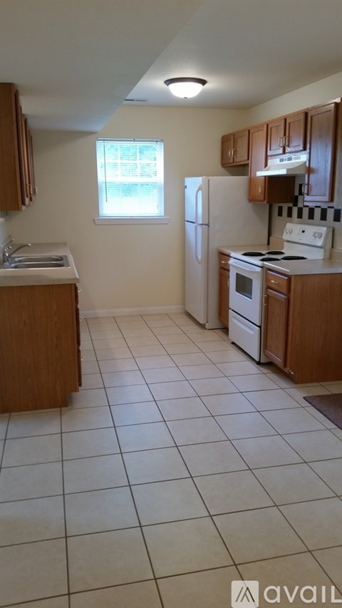 A kitchen with white tile flooring and wooden cabinets.