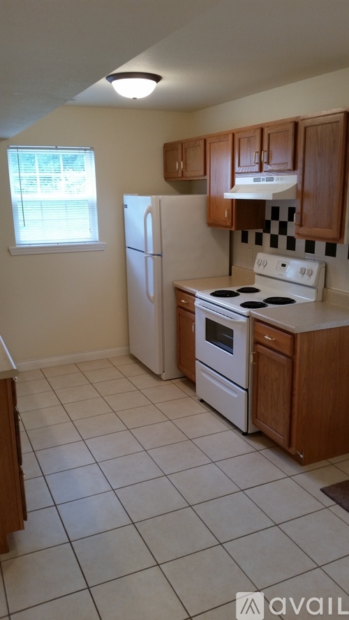 A kitchen with a white fridge, white stove, and white tile flooring.