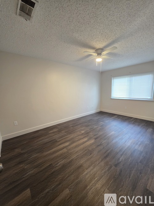 A room with a ceiling fan and wooden flooring.