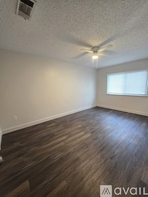 A room with a ceiling fan and wooden flooring.