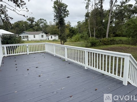 A wooden deck with a white railing and a house in the background.