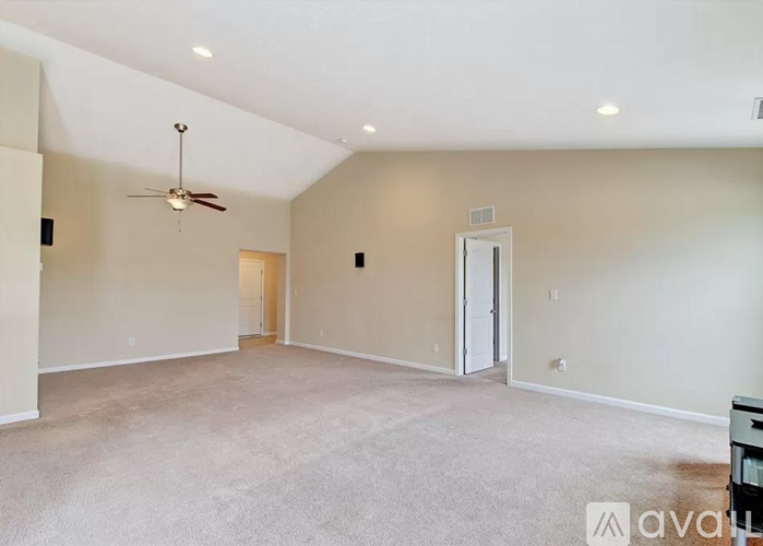 A spacious room with a ceiling fan and carpeted floor.