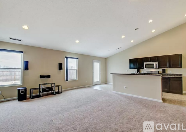 A spacious living room with a kitchen area in the background.