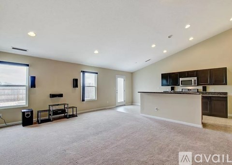 A spacious living room with a kitchen area in the background.