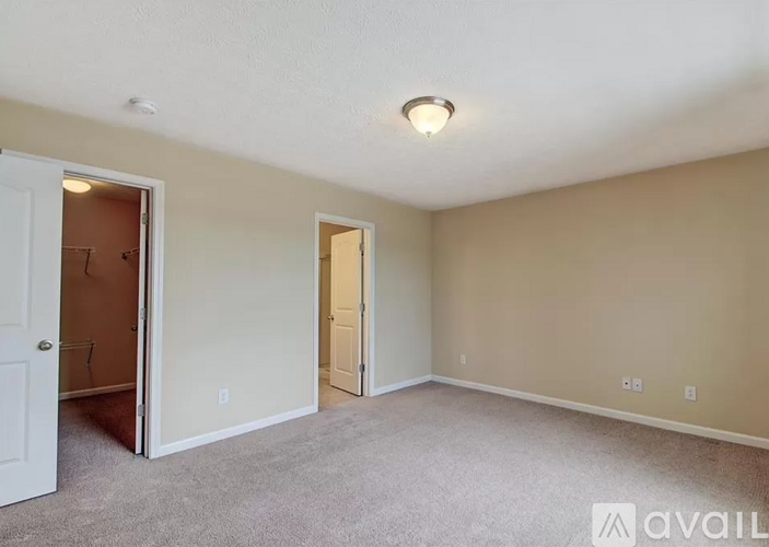 A room with a carpeted floor and two doors, one of which is open.
