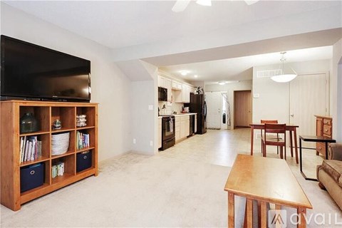 A living room with a television, a wooden bookshelf, and a dining area.