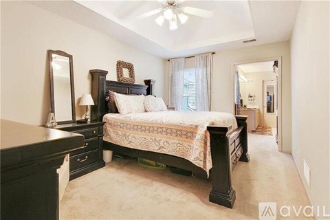 A bedroom with a large bed, a dresser, and a mirror.