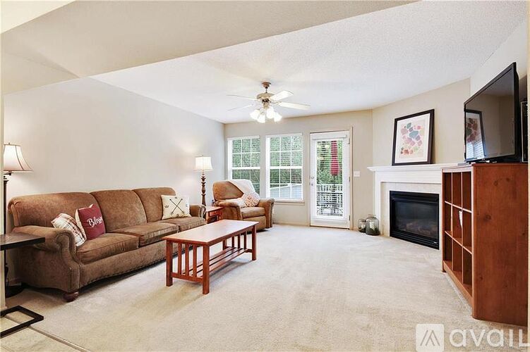 A living room with a brown couch, a coffee table, a fireplace, and a television.